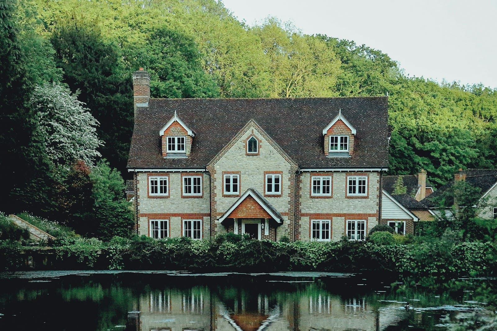 A stone home beside a quiet wooded lake